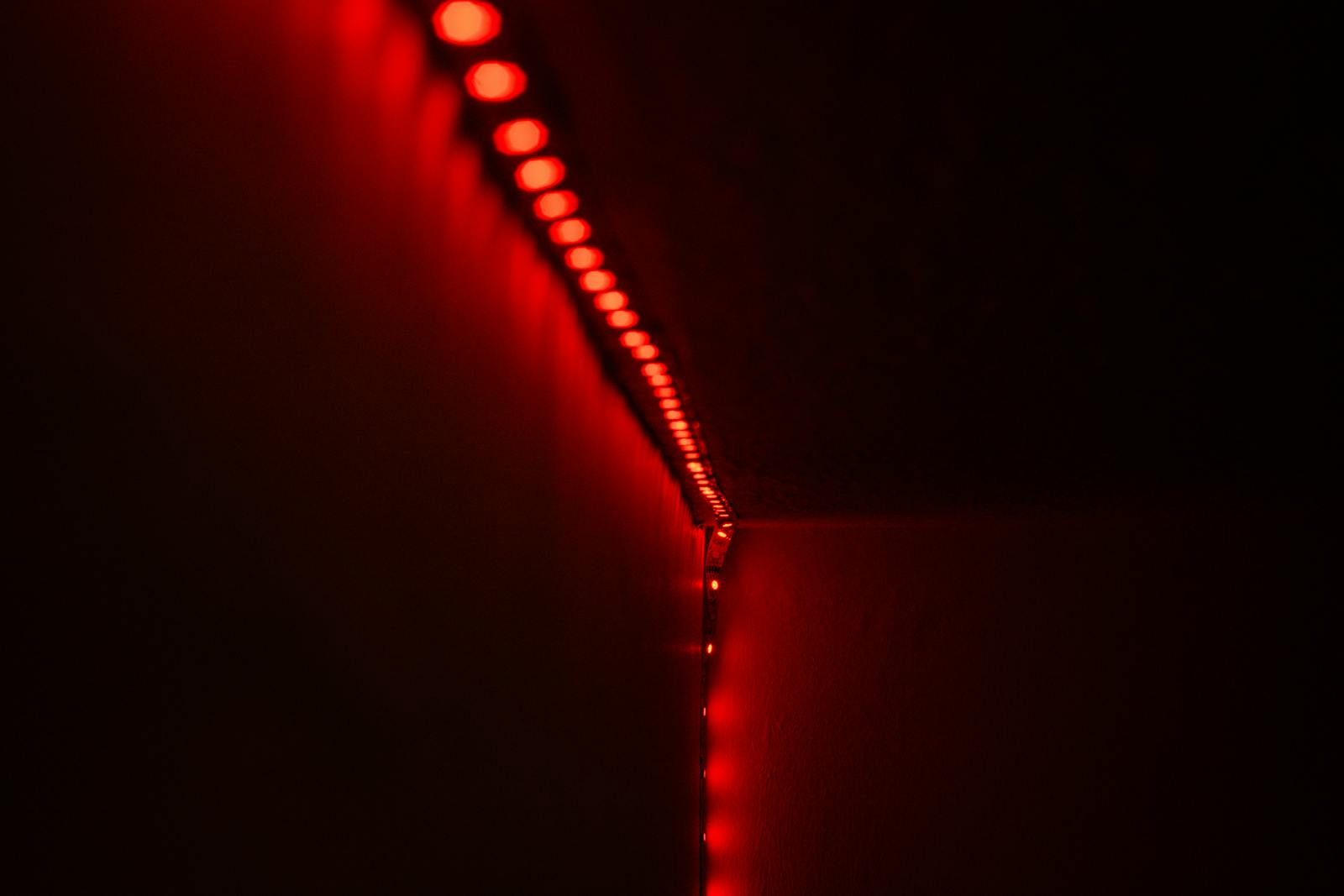 Glowing red LED strip light on a dark wall